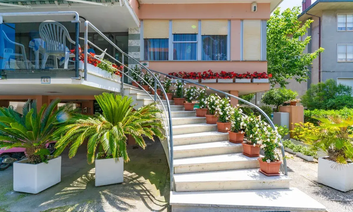 L'ingresso fiorito del hotel dell'amarissimo, con scale bianche ornate da piante e fiori, invita ad entrare.