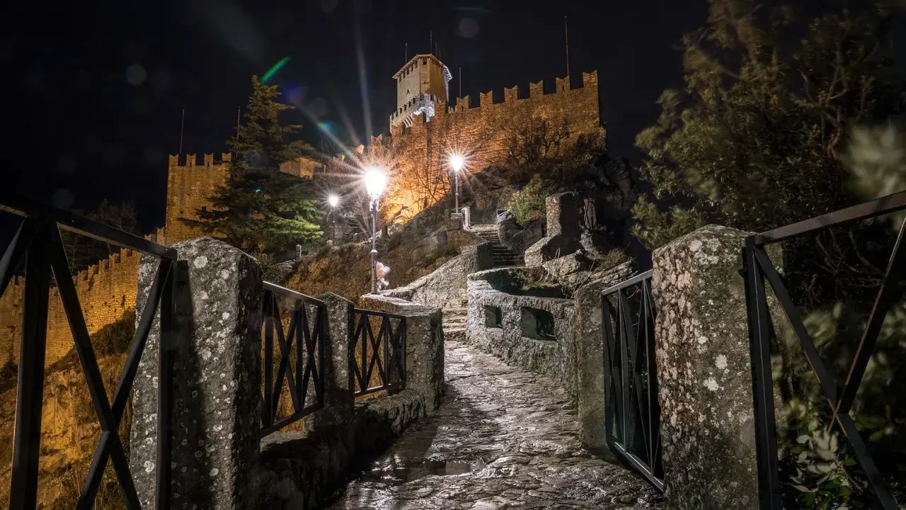 Sentiero lastricato di notte, illuminato da lampioni, conduce verso il castello di San Marino, il passo delle streghe.