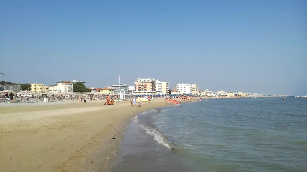 Spiaggia affollata a Viserbella mare, con ombrelloni, lettini e persone che si godono il sole e il mare azzurro sotto un cielo limpido.