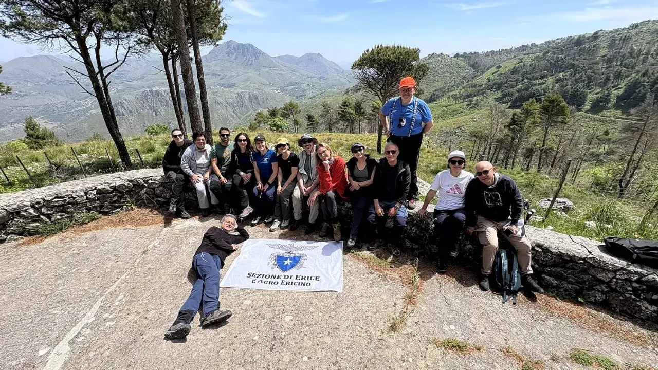 Gruppo di escursionisti con bandiera della Sezione di Erice e Agro Ericino, in cima al monte Gradara, con vista panoramica sulla valle.