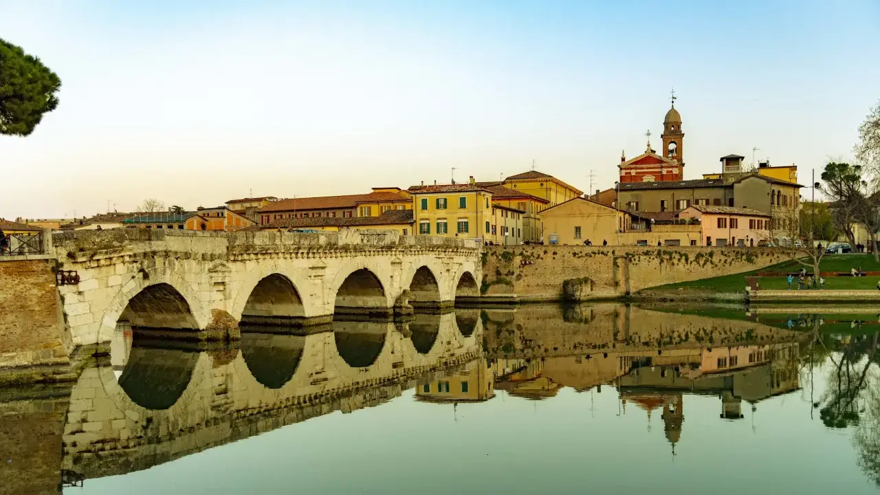 Ponte di Tiberio a Rimini, un luogo che evoca la magia di Fellini, con le sue arcate che si specchiano nell'acqua calma.