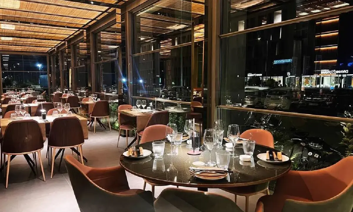 Interni eleganti del miglior ristorante di Rimini, con tavoli apparecchiati e vista notturna sulla città.