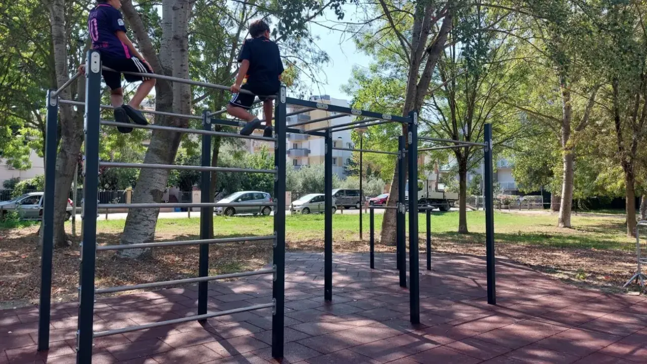 Bambini si arrampicano su una struttura per esercizi all'aperto nel parco Briolini a Rimini.