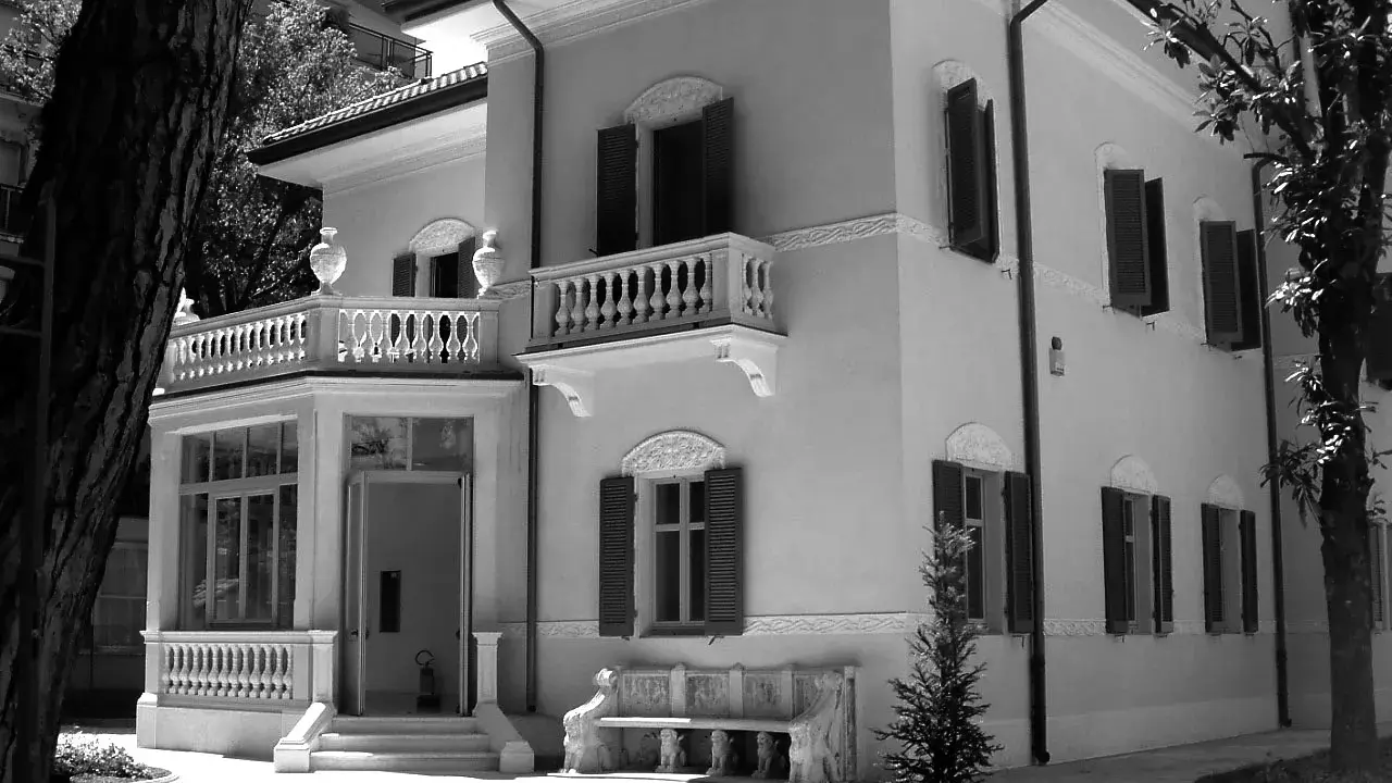 Villa Franceschi a Riccione, un'elegante dimora con balconi e un ingresso accogliente, circondata da alberi e un giardino curato.
