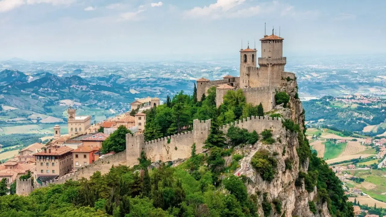 Torri medievali su un monte roccioso, con vista panoramica sulla campagna circostante, un paesaggio che ricorda la vicinanza di San Marino a Rimini.