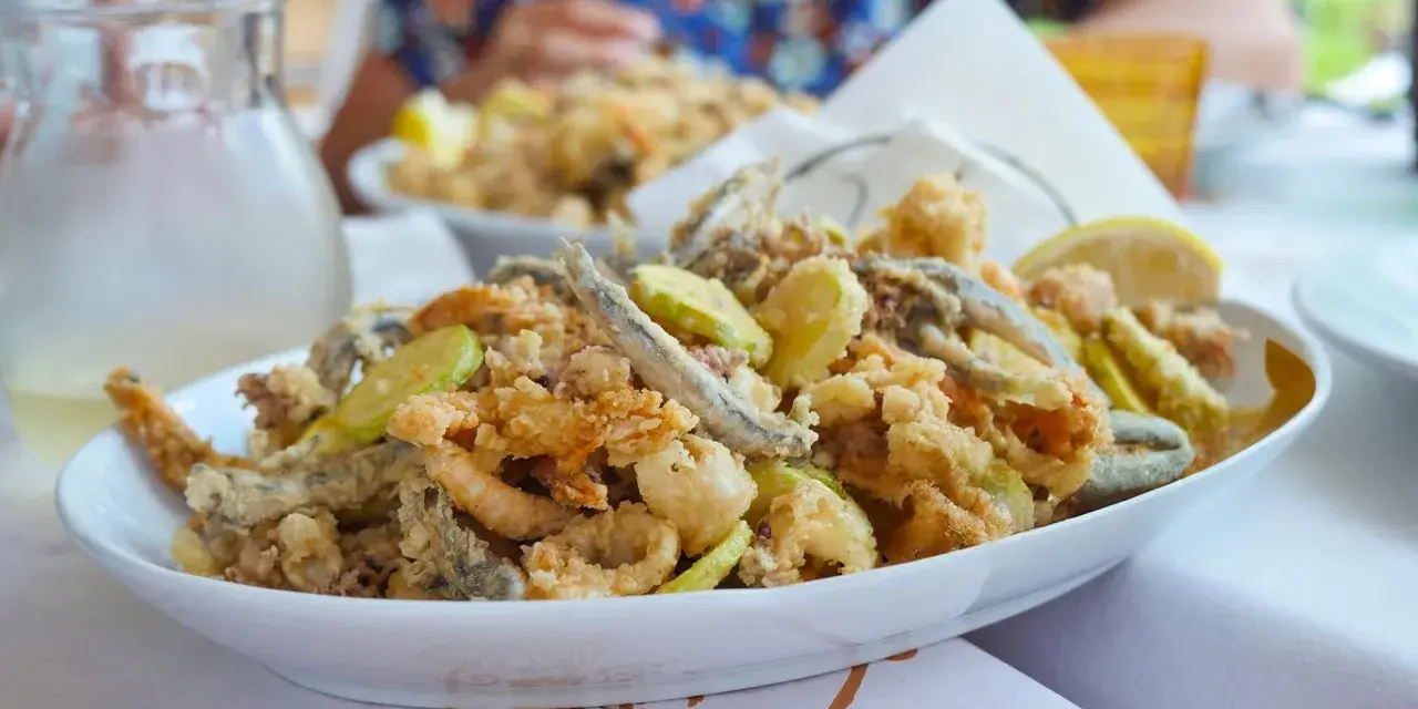 Fritto misto di pesce e verdure, un'ottima idea per cosa mangiare a Riccione. Croccante e saporito, perfetto con una caraffa di vino bianco.
