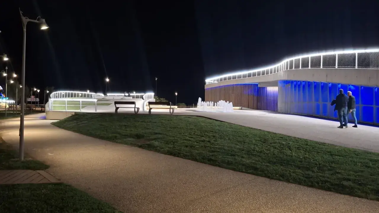 Passeggiata serale a **Piazzale Kennedy Rimini**, con fontane luminose e architettura moderna illuminata.