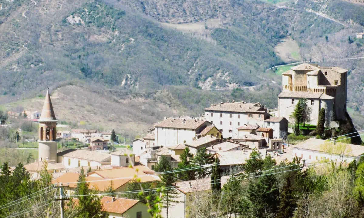 Borgo medievale con torre campanaria e rocca imponente, immerso tra le colline verdi. Un angolo di storia vicino a Marecchia Rimini.