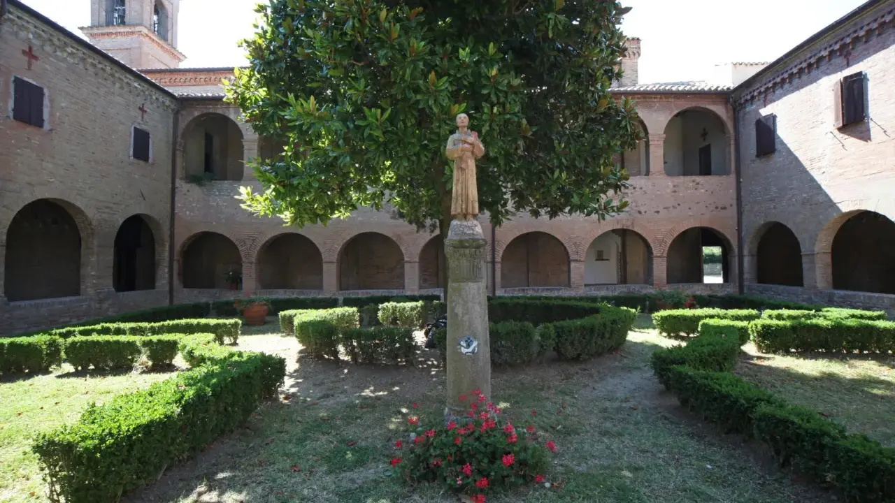 Cortile di una villa a Verucchio con statue, alberi e siepi curate.