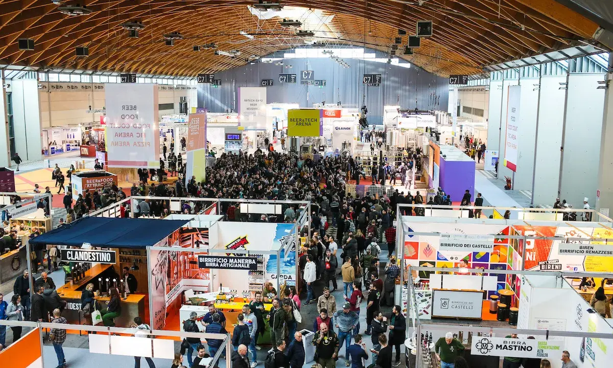 Folla in un padiglione fieristico, un'attrazione beer&food con stand e degustazioni.