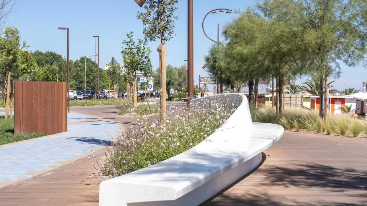 Passeggiata moderna con panchina bianca e fiori sulla bellariva di Rimini.