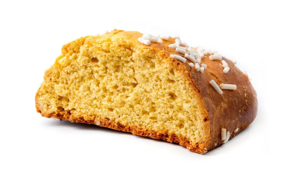 Fetta di ciambella, un dolce tipico romagnolo, con zuccherini bianchi sparsi sulla crosta dorata.