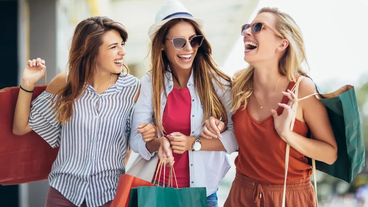Tre amiche ridono felici con borse della spesa, dopo un pomeriggio di shopping nel cesenatico centro negozi.