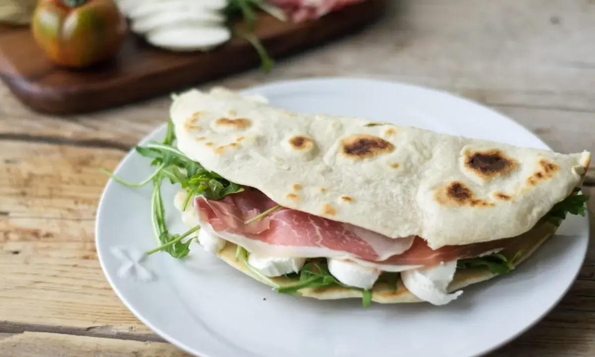 Piadina farcita con prosciutto crudo, mozzarella e rucola. Ecco come si farciscono le piadine per un pasto veloce e gustoso.