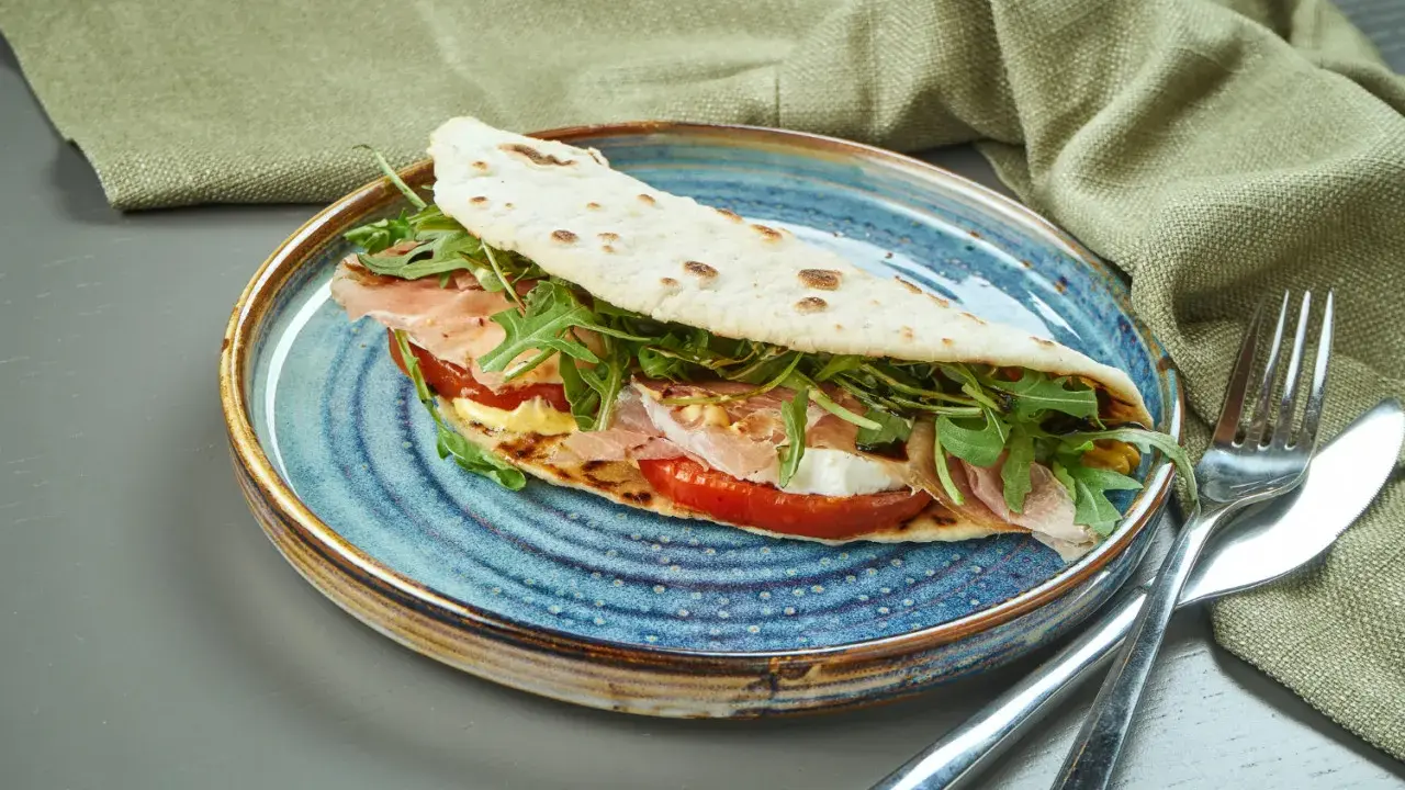 Piadina romagnola con prosciutto, mozzarella, pomodoro e rucola, un classico del rimini food.
