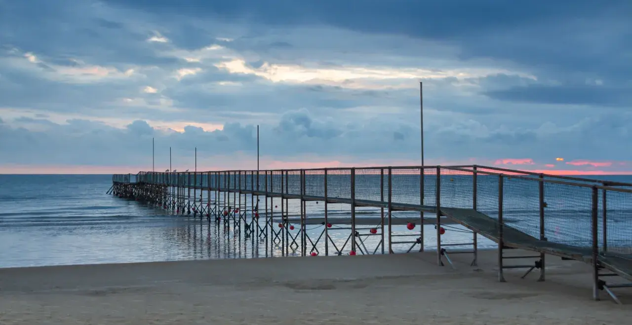 Molo di Rimini Rivazzurra al tramonto, con cielo nuvoloso e mare calmo.