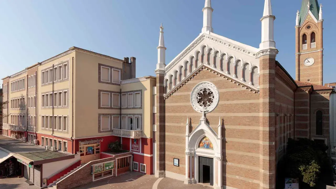 Facciata di una chiesa a Rimini con campanile e edificio adiacente.