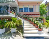 L'ingresso fiorito del hotel dell'amarissimo, con scale bianche ornate da piante e fiori, invita ad entrare.