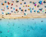 Un'affollata spiaggia di Rimini mare, con ombrelloni colorati e bagnanti che si godono il sole e il mare cristallino.