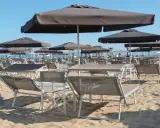 Lettini e ombrelloni scuri sulla sabbia dorata della **Baia degli Angeli Misano**, pronti per accogliere i bagnanti sotto il sole.