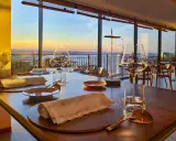 Tavola apparecchiata in un ristorante stellato a Gabicce Monte, con vista sul tramonto sul mare.