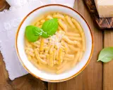 Piatto di passatelli in brodo, un classico dei piatti romagnoli, guarnito con basilico fresco e parmigiano.