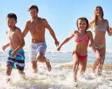 Famiglia corre felice nel mare del lido di Savio, spruzzi d'acqua e sole.