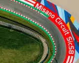 Vista aerea del circuito di Misano, con la scritta "Misano Circuit Sic58" in rosso e un disegno colorato.