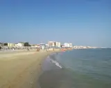 Spiaggia affollata a Viserbella mare, con ombrelloni, lettini e persone che si godono il sole e il mare azzurro sotto un cielo limpido.