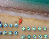 Ombrelloni blu e gialli e una barca rossa sulla spiaggia di Misano Marittima, con il mare turchese sullo sfondo.