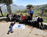 Gruppo di escursionisti con bandiera della Sezione di Erice e Agro Ericino, in cima al monte Gradara, con vista panoramica sulla valle.