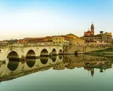 Ponte di Tiberio a Rimini, un luogo che evoca la magia di Fellini, con le sue arcate che si specchiano nell'acqua calma.