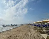 Pedalò in acqua e file di lettini e ombrelloni su una spiaggia sabbiosa, tipica di un bagno Roma di Levante.