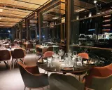 Interni eleganti del miglior ristorante di Rimini, con tavoli apparecchiati e vista notturna sulla città.