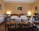 Camera elegante con due letti singoli, un tavolino con champagne e pasticcini, e sedie d'epoca. Un assaggio di lusso al Grand Hotel Rimini.