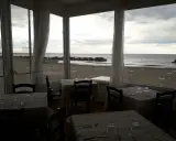 Tavoli apparecchiati in un ristorante con vista sulla spiaggia di Misano durante la bassa marea.