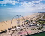 Vista aerea delle spiagge romagna con ruota panoramica, ombrelloni e mare azzurro.