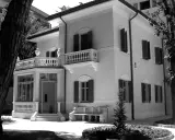 Villa Franceschi a Riccione, un'elegante dimora con balconi e un ingresso accogliente, circondata da alberi e un giardino curato.