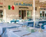 La Marianna Rimini, trattoria sul mare, con tavoli apparecchiati all'esterno sotto un grande albero.