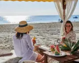Due donne sorseggiano cocktail in un bagno Jacarè a Cervia, godendosi la spiaggia e il mare.