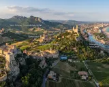 Panoramica aerea di borghi medievali e colline verdi, con il mare Adriatico sullo sfondo. Si vedono San Leo, Gradara, Santarcangelo e Cesenatico, un viaggio tra storia e natura in Romagna.