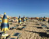 Ombrelloni a righe blu e gialle e lettini vuoti sulla spiaggia di Rivazzurra, in attesa dei bagnanti.