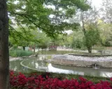 Un laghetto con un ponticello in legno e aiuole fiorite nel Parco della Resistenza a Riccione.