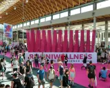 Folla animata a Rimini Wellness, un evento dedicato al benessere e al fitness. Persone di ogni età passeggiano tra gli stand e le aree espositive.