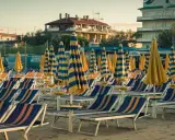 File di sdraio e ombrelloni a righe blu e gialle sulla spiaggia di Cervia Milano Marittima, pronti per accogliere i bagnanti.