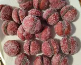 Dolci castagnole romagnole, due semisfere rosse unite da una crema scura e ricoperte di zucchero.