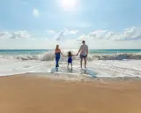 Famiglia felice sulla riviera romagnola con bambini, godendosi le onde del mare.