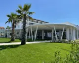 Palme e prato verde davanti a un moderno ristorante a Bellaria Igea, con un edificio bianco sullo sfondo.