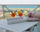 Due aperitivi arancioni e asciugamani con logo "Hotel Rivazzurra Rimini" sul tavolo, con vista sul rivazzurra mare e spiaggia attrezzata.