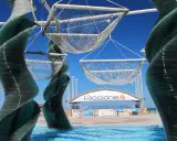Sculture di vetro e reti sospese, con la scritta "Riccione" in lontananza. Un'idea di cosa vedere a Riccione, tra arte e mare.